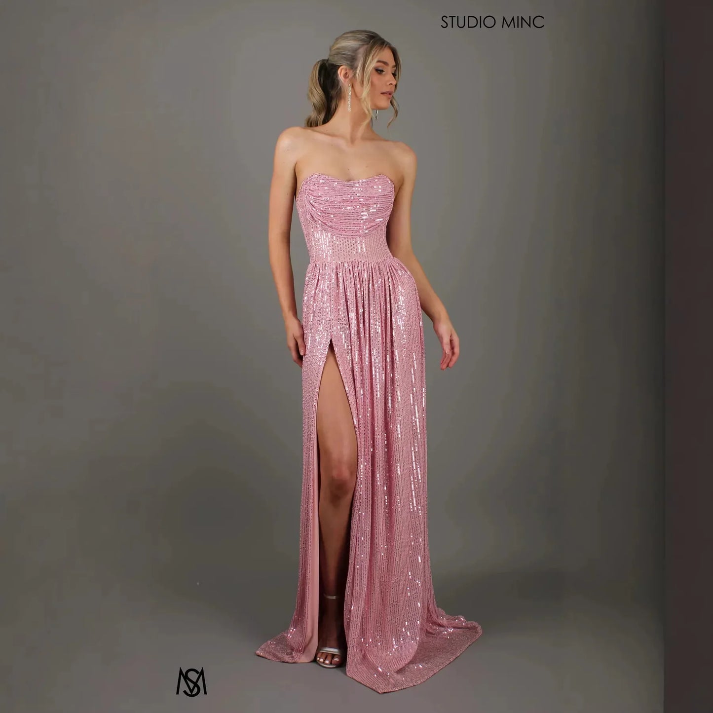 Pink sequin strapless evening gown with high slit and ruched bodice, perfect for prom or formal events