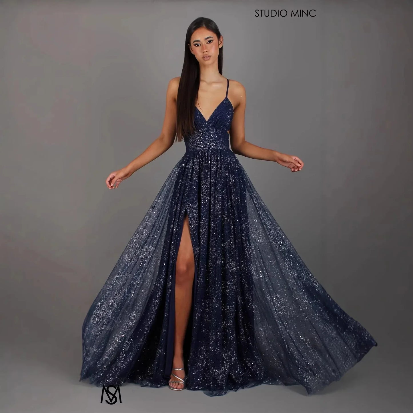 Navy blue sparkly A-line evening gown with V-neck, thin straps, and high slit for prom or formal events