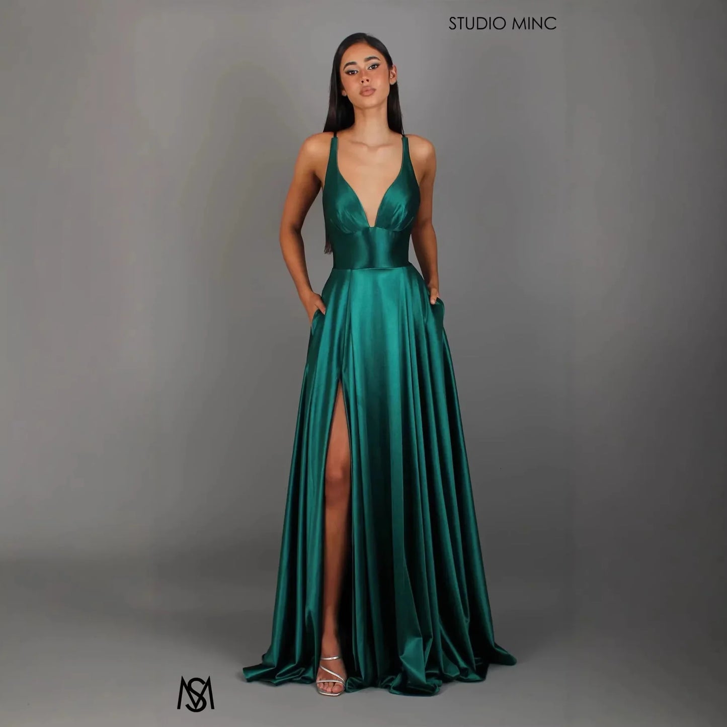 Emerald green satin evening gown with deep V-neck, high slit, and pockets, ideal for formal events and prom