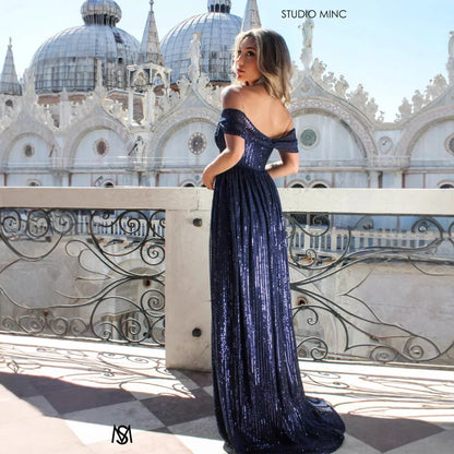 Navy blue sequin off-shoulder maxi dress with flowing skirt, perfect for evening events and formal occasions.