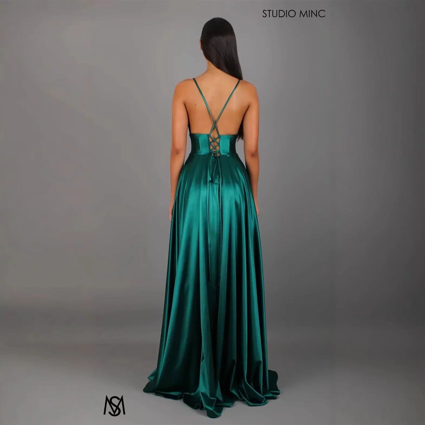 Emerald green satin evening gown with crisscross back straps and lace-up detail, floor-length formal dress