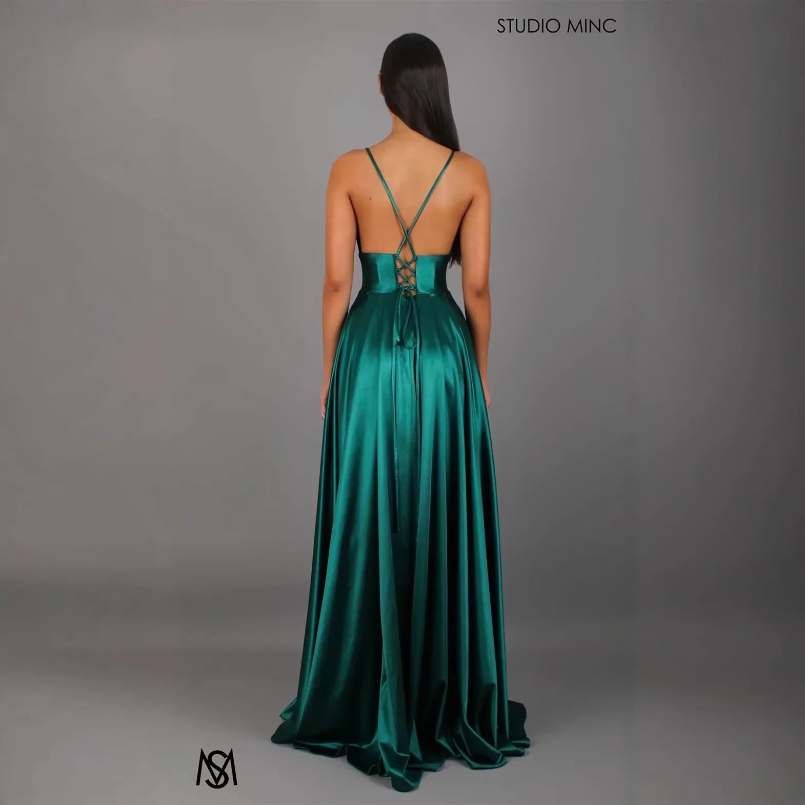 Emerald green satin evening gown with crisscross back straps and lace-up detail, floor-length formal dress